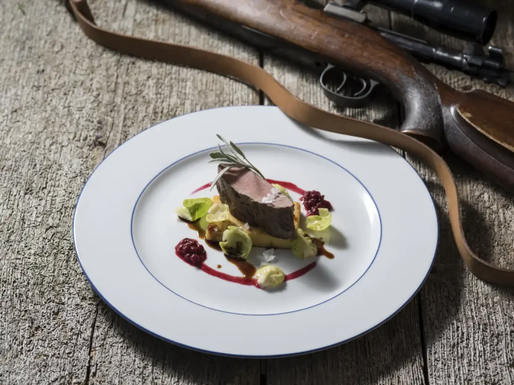 Feines Wildgericht vom Gasthof Pack, im Hintergrund ein schönes Jagdgewehr